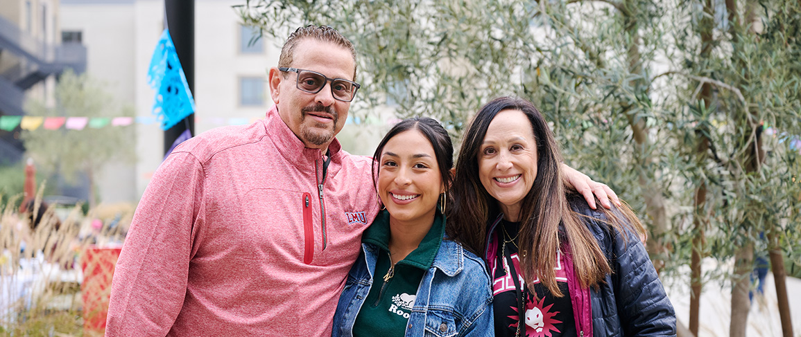 Three members of the LMU community pose together outdoors on campus during a university event